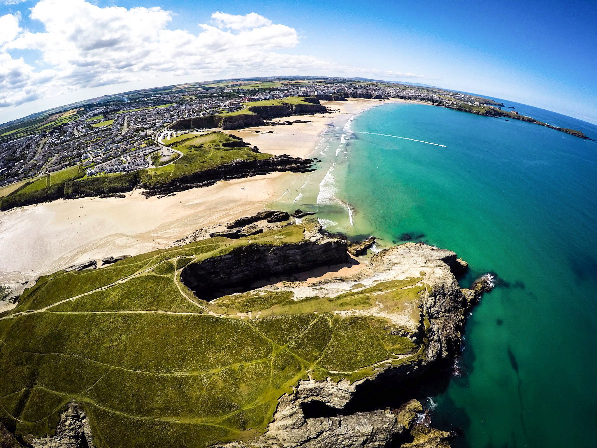 Aerial view across a coastal town, sandy beaches, cliffs and turquoise sea