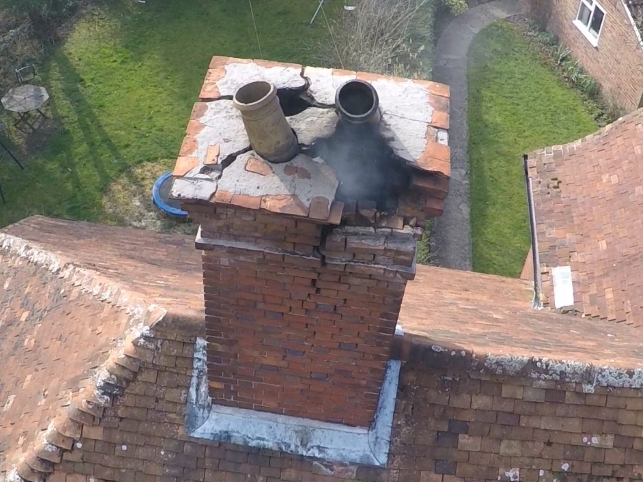 Aerial view of a brick chimney stack and adjoining tiled roofs